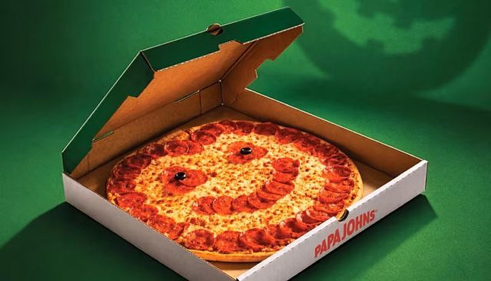 Papa Johns Jack-O'-Lantern Pizza with a pepperoni smile and olive eyes in an open box