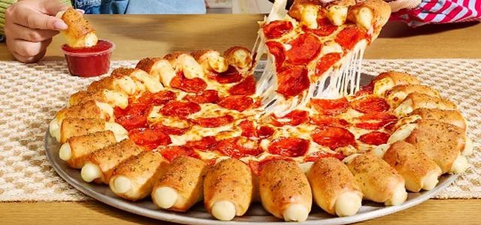 Pizza Hut Cheesy Bites Stuffed Crust pepperoni pizza with a bite dipped in marinara